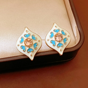 Macro detail of vintage diamond-shaped heart earrings with gold trim and champagne gems