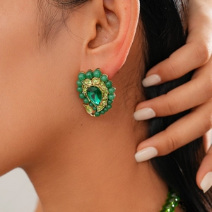 Detail shot of vintage green teardrop earring with crystals worn by a model