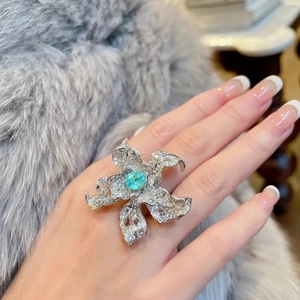 Luxury starfish flower ring with blue-green gemstone and sparkling crystals on model