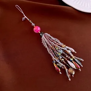 Elegant beaded phone charm featuring pink crystal butterfly and layered tassel on velvet