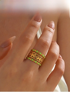 Macro view of gold-plated rings with emerald green enamel and sunflower relief details
