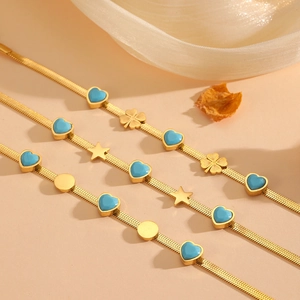 Détail de bracelets chaîne serpent dorés avec pendentifs cœur bleu et étoile