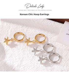 Detailed view of starfish pendant hoop earrings in gold and silver on white fabric