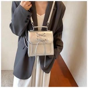 Silver metallic backpack with bow detail and ribbon straps shown on a model