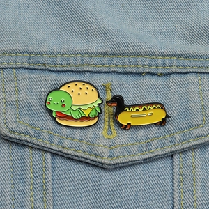 Broches créatives en métal tortue-burger et chien-hot-dog sur une veste en jean bleue