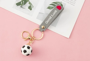 Detail of soccer keychain with grey silicone Good Luck strap and gold lobster clasp