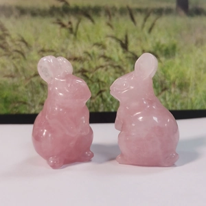 Macro detail of two pink crystal bunny figurines in a sitting pose on a white surface
