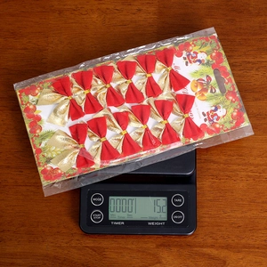 Detailed view of 12 red and gold velvet Christmas bows on a precision digital scale