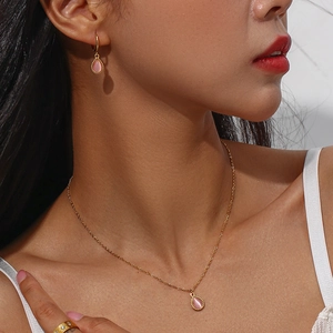 Detail shot of gold necklace and earring set featuring pink teardrop cat eye stones