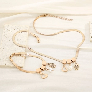 Detail shot of gold snake chain jewelry set with heart charms and white pearls on silk
