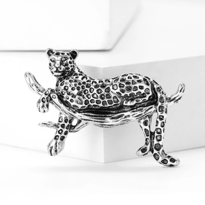 Macro shot of silver leopard brooch on white cube with elegant spot details