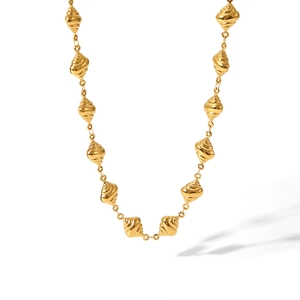 Dettaglio di perle a spirale dorate su collana lunga con lucentezza metallica vintage