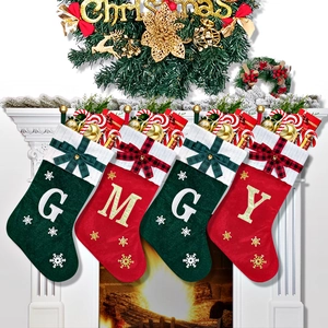 Detail of embroidered Christmas stockings with letters and bows hanging by a fireplace