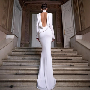 Elegante abito da sera bianco con schiena scoperta e taglio a sirena su scala di marmo