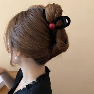 Detail of red bead accent on black flocked claw clip holding a stylish updo hairstyle