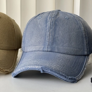 Detail of distressed washed denim baseball caps with worn edges and vintage texture