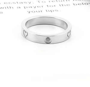Macro detail of silver heart ring featuring a centered round cubic zirconia stone