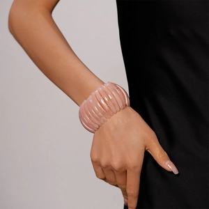 Détail d'un bracelet en résine rose à texture côtelée porté par un mannequin en noir