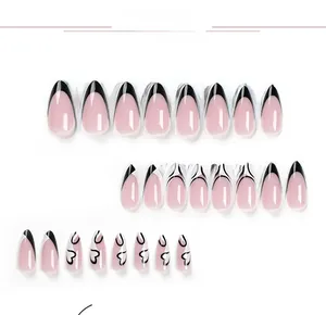 Detail of pink almond fake nails with black French tips and heart patterns on white back