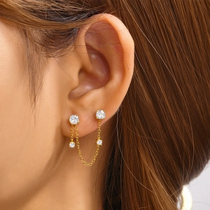 Detail of gold-plated chain earrings with sparkling zircons worn on a real ear