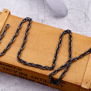 Close-up of retro black titanium steel twisted chain necklace on a rustic wooden box