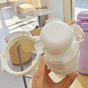 Close-up of white sports water bottle with flip top lid, carry ring and silicone sleeve