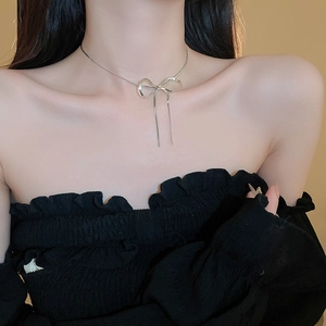 Detail shot of a silver bow snake chain necklace worn by a model for a minimalist aesthetic