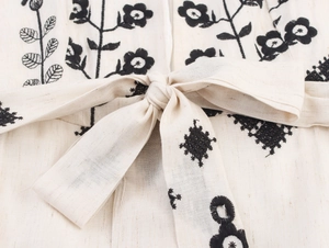 Detail of waist drawstring and floral embroidery on beige linen dress