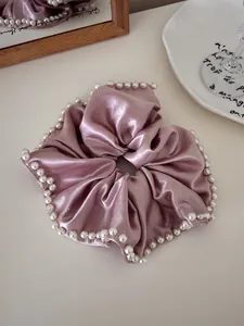 Detail of lavender satin hair scrunchie with elegant faux pearl trim and silky texture