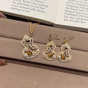Detailed shot of golden stainless steel gourd necklace and earring set with brown tiger eye stone