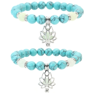 Close-up of turquoise beaded bracelets featuring silver lotus flower charms on white background