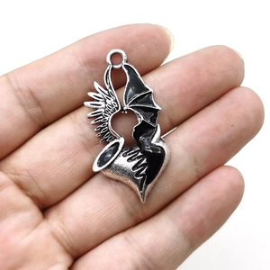 Gothic heart pendant with silver angel wing and black bat wing on a white background