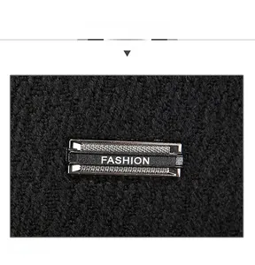 Macro detail of black knit fabric with a metallic FASHION emblem on the cap side