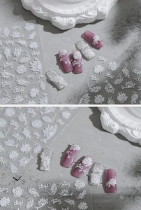 Macro detail of white embossed floral nail art stickers with daisy patterns and text