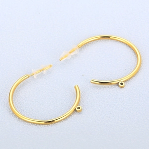 Golden round C-shaped hoop earrings with clear backings on a light blue textured surface