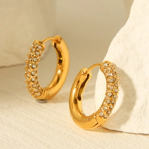 Detailed close-up of 18K gold plated hoop earrings with pave cubic zirconia on a stone surface