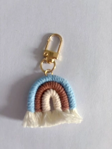Detailed macro view of a handmade woven cotton rainbow keychain with golden D-ring clasp
