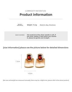 Detail view of large rectangular red rhinestone earrings with brushed gold finish