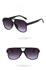 Detail view of double bridge aviator sunglasses with glossy black frame and gradient grey lenses