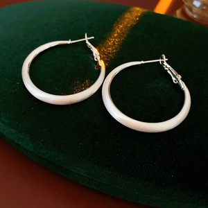 Macro detail of silver frosted hoop earrings with textured finish on green velvet