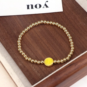 Close-up of golden beaded bracelet with a vintage religious medallion on dark wood