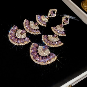 Macro shot of triple-layer fan earrings with purple teardrop gems and white crystals