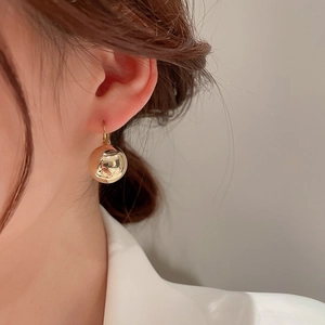 Gros plan sur boucle d'oreille boule dorée minimaliste pour femme avec finition miroir polie