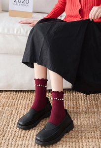 Detail of burgundy crew socks with ruffled cuffs and decorative white pearl embellishments
