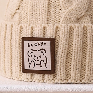 Chunky cable knit winter beanie for children in cream white with a lucky bear patch