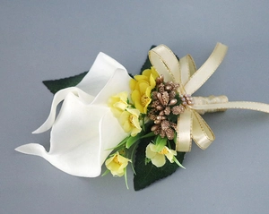 Detail of calla lily wedding boutonniere with white petals and champagne silk ribbon