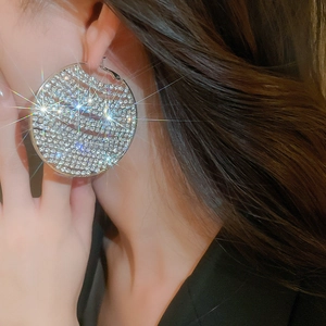 Close-up of a woman wearing large silver-toned hoop earrings with shimmering rhinestones