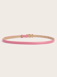 Detail of pink thin leather belt featuring a golden bow buckle on a beige background