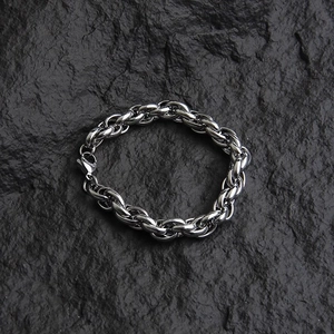 Men's heavy silver titanium steel chain bracelet on a textured dark rock background