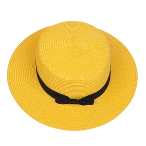 Detailed top view of a yellow straw boater hat with a black ribbon bow and woven texture